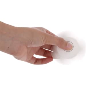 A fidget spinner is held in a hand, featuring a simple white design with a circular centre.