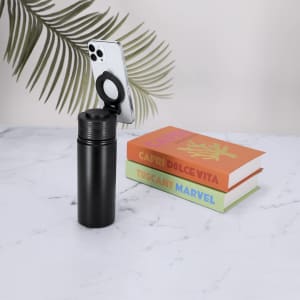 A drink bottle in black, with a fitted cap, standing next to two colourful books and a smartphone holder.
