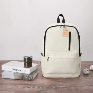 A backpack in cream with a front pocket, accompanied by a drink cup, books, and decorative cotton branches.