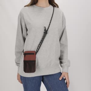 A grey sweatshirt and denim jeans complement a brown mesh-sided multipurpose bag with a shoulder strap.