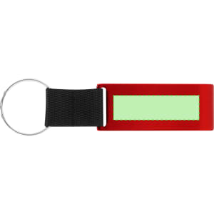 A red keyring with a black strap and a blank green label area, featuring a silver circular keyring attachment.