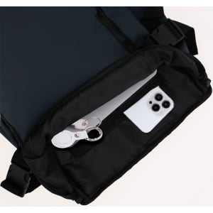 A navy Rigan Backpack, partially unzipped, revealing a phone and keys inside a black compartment.