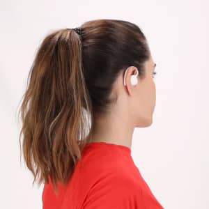 White Gumex headphones are worn by a person with brown hair tied in a ponytail, facing away from the camera.