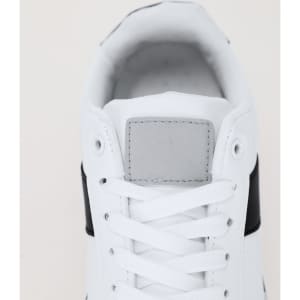 A pair of trainers featuring a white upper with black accents and laces. The shoe has a logo on the tongue.
