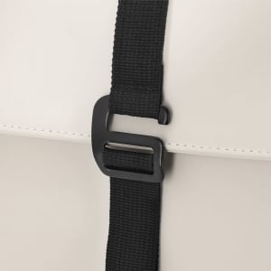A close-up of a cream-coloured backpack featuring a black strap and buckle. The backpack has a smooth texture.