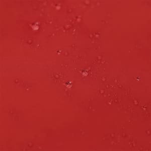 A close-up of a red puffer jacket fabric with drops of water on its surface, showcasing its water-resistant quality.