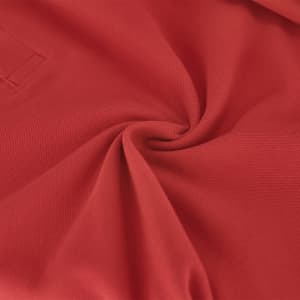 A red polo shirt featuring a textured fabric, showcasing a smooth swirl pattern with a simple logo.