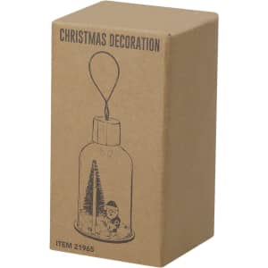 A brown cardboard box containing a Christmas decoration, featuring an illustration of a glass ornament with a forest scene.