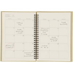 A monthly planning notebook with a spiral binding, featuring blank calendar pages and a light brown cover.