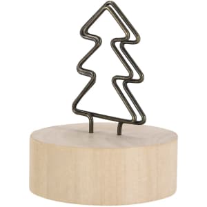 A decorative metal tree silhouette sits atop a round wooden base. The tree is outlined in a dark metallic finish.