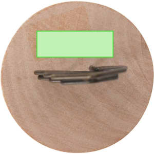A metal clip with a sleek design positioned on a wooden surface. The clip features a logo on its body.