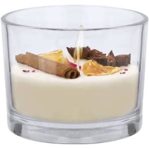A glass candle featuring a blend of white wax, cinnamon sticks, and dried orange slices, with a decorative top.