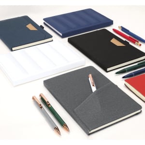 A collection of notebooks in various colours including grey, black, navy, red, and white, accompanied by pens and pencils.