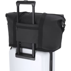 A black extendable bag rests on top of a wheeled suitcase, featuring a zippered pocket and a handle.
