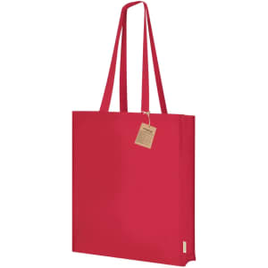 A red tote bag with long straps, featuring a tag and a simple design, and a logo on one side.