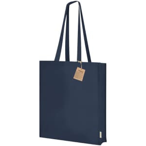 A navy blue tote bag with long handles and a tag attached. The bag has a simple, minimalist design.