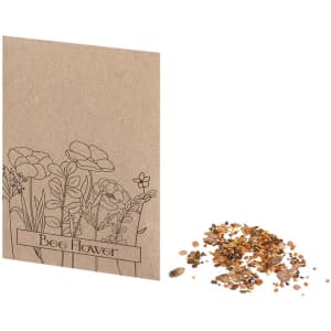 A seed packet with a floral design in brown, alongside a pile of assorted seeds for planting.