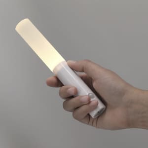 A white torch being held, featuring a long light source emitting a soft glow. It has a simple design and a button.