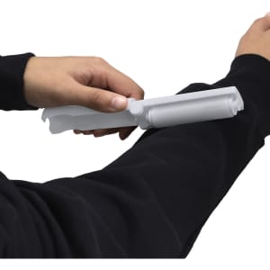 A lint remover in white being used on a black sweatshirt sleeve, featuring a simple design and handle.
