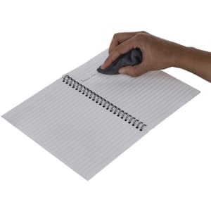 A hand erasing text from a spiral-bound, lined notebook with a grey eraser. The notebook has a simple design.