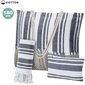 A striped cotton tote bag in navy and white, accompanied by a matching towel and cushion. Features a woven handle.