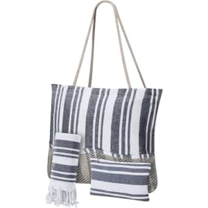 A striped tote bag in navy and white with a textured bottom, accompanied by a matching towel and small cushion.
