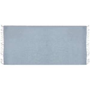 A light blue drawstring bag pareo featuring fringed edges and a smooth texture, with branding visible.