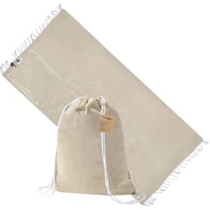 A beige drawstring bag and a matching pareo with fringed edges, featuring a small pocket and a logo.