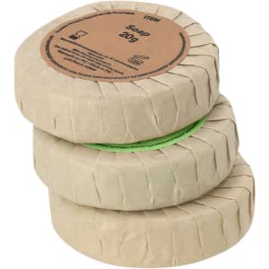 A stack of three circular soap bars wrapped in brown and green paper, with a logo on the packaging.