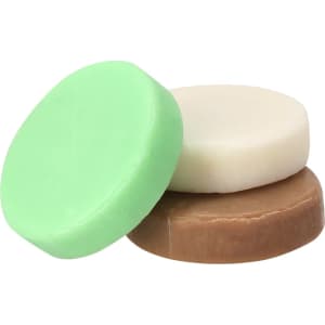 A set of three circular soaps in green, cream, and brown colours, with a simple, smooth design.