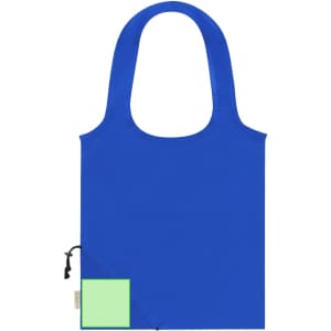 A blue foldable tote bag with a green square section and a logo on the front.