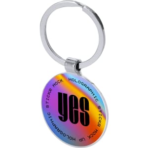 A holographic keyring with a circular design, featuring the word "yes" in bold black text on a vibrant, multi-coloured background.
