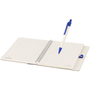 A notebook with a spiral binding open to lined pages, accompanied by a blue pen. It features a logo on the cover.