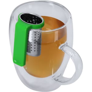 A clear tea mug with a green infuser and light brown tea inside. The mug features a handle and a stainless steel strainer.