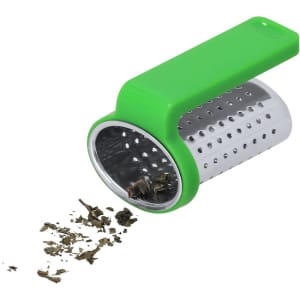 A tea infuser with a green silicone handle and a stainless steel mesh body, featuring loose tea leaves spilling out.