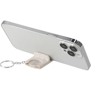 A keyring coin holder in a beige colour, attached to a smartphone, providing a stable stand.