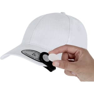 A white cap with a black clip for attaching a marker, and a person's hand holding a small round marker.