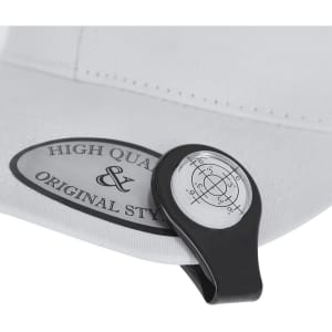 A black and white golf ball marker with a leveler attached to a white cap's tag.