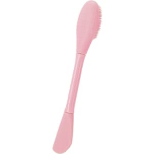 A pink facial spatula with a textured side and a brush tip, designed for beauty and personal care routines.