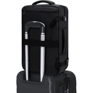 A black Garnep Vacuum Backpack resting on top of a suitcase, with a retractable handle visible.