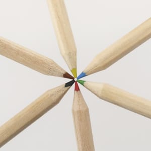 A set of coloured pencils with wooden shafts, featuring tips in various colours: red, green, blue, yellow, black, and brown.