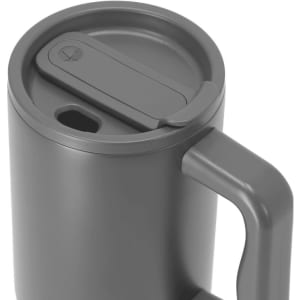 A grey insulated travel mug with a lid and handle, featuring a logo on the side.