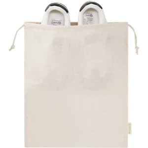A cream-coloured tote bag filled with white shoes, featuring a drawstring closure and a branding logo.