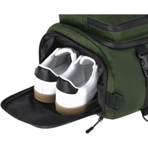 A green backpack bag with a compartment containing white sneakers with black accents. The bag features a logo.