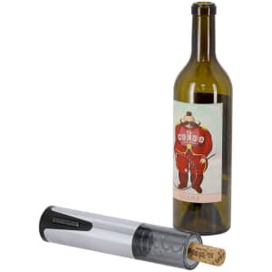 A silver electric corkscrew next to a green wine bottle with a cartoonish label. The cork is partially removed.