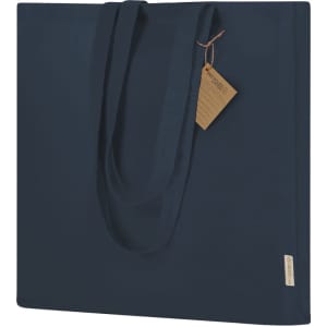 A navy tote bag with long handles and a tag. The bag has a simple, solid design and a branding logo.