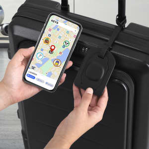 A black luggage tag with a tracker attached to a suitcase, alongside a smartphone displaying a map.