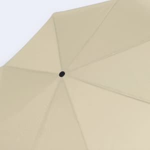A beige umbrella with a black centre button and a symmetrical, eight-panel design.