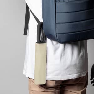 A beige umbrella attached to a backpack, against a plain grey background. The backpack is navy blue.