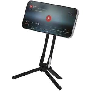 A black phone stand with three adjustable legs holding a smartphone displaying media content.